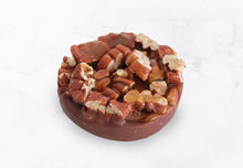 Mini pecan pie with visible caramel and glossy pecans on top, and a chocolate-covered bottom crust.